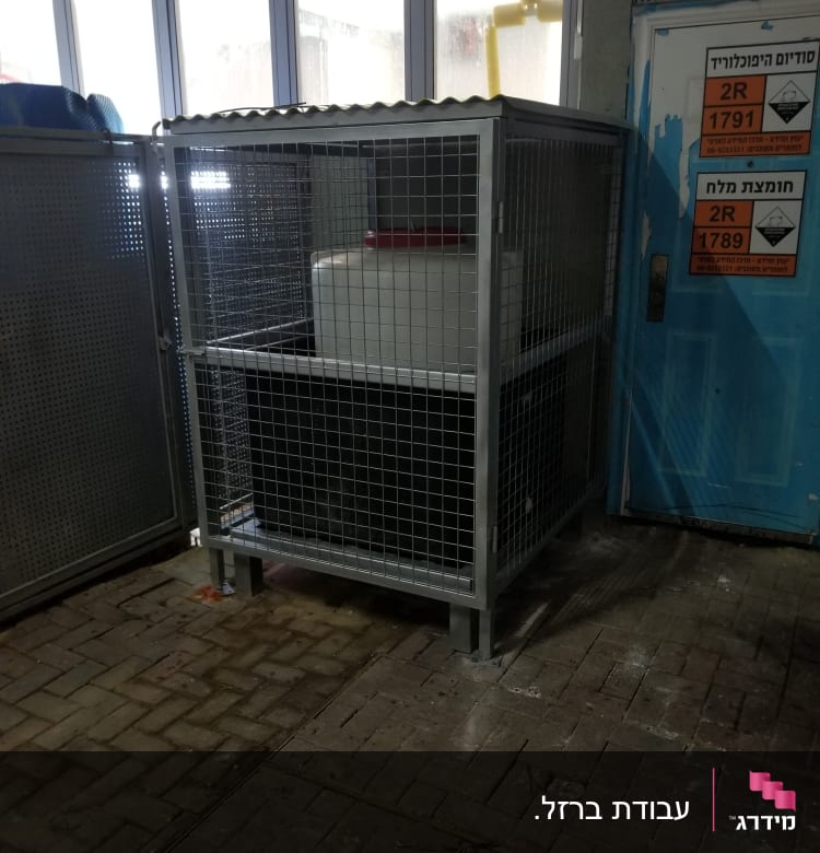 כלוב מתכת עם מסגרת רשת על רצפת לבנים